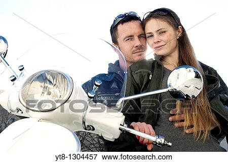 Stock Photo - Couple sitting on a motor scooter and embracing. Fotosearch