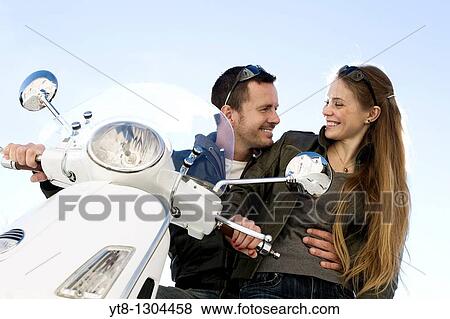 Stock Photo - Couple sitting on a motor scooter and embracing. Fotosearch
