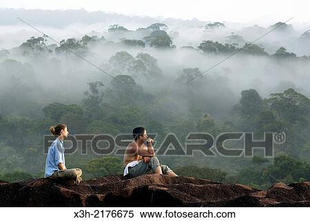 couple sitting on an inselberg above the forest canopy, hiking in the forest, French Guiana, overseas department and region of France, Atlantic coast of South America. View Large Photo Image Stock Photography - couple sitting on an inselberg above the forest canopy, hiking in the forest, French Guiana, overseas department and region of France, Atlantic coast of South America.. Fotosearch