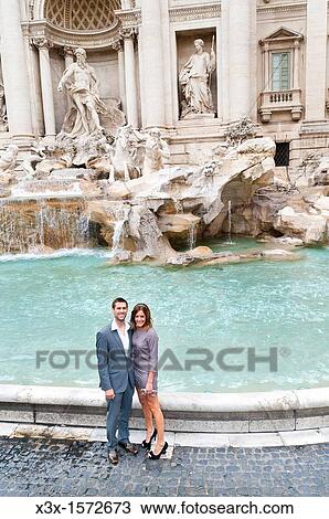 Couple sitting on the edge of the Trevi fountain in Rome Italy View Large Photo Image Stock Image - Couple sitting on the edge of the Trevi fountain in Rome Italy. Fotosearch