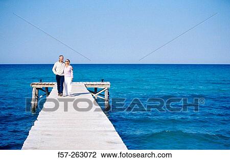 Couple sitting walking in a wooden footbridge over the sea View Large Photo Image Stock Image - Couple sitting walking in a wooden footbridge over the sea. Fotosearch