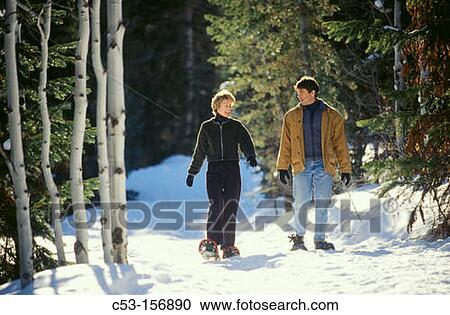 Stock Image - Couple snowshoeing in the woods. Fotosearch
