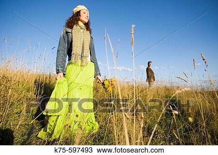 Stock Image - Couple standing apart in field. Fotosearch
