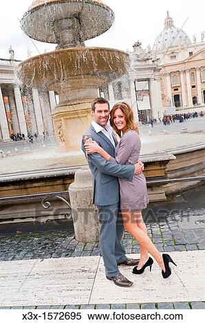 Couple standing in front of a water fountain in Saint Peter's square Rome Italy View Large Photo Image Stock Photography - Couple standing in front of a water fountain in Saint Peter's square Rome Italy. Fotosearch