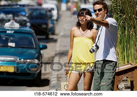 Stock Image - couple standing on sidewalk and pointing. Fotosearch