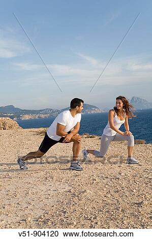 Couple stretching by the sea in a cliff in Ibiza View Large Photo Image Stock Image - Couple stretching by the sea in a cliff in Ibiza. Fotosearch
