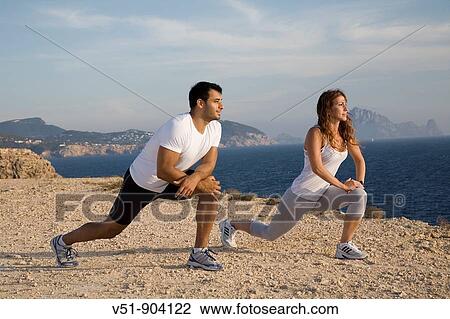 Couple stretching by the sea in a cliff in Ibiza View Large Photo Image Stock Image - Couple stretching by the sea in a cliff in Ibiza. Fotosearch