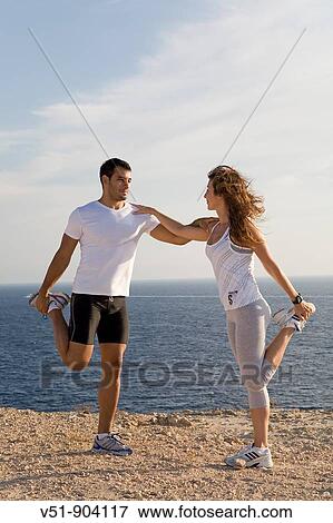 Couple stretching by the sea in a cliff in Ibiza View Large Photo Image Stock Photo - Couple stretching by the sea in a cliff in Ibiza. Fotosearch