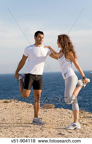 Couple stretching by the sea in a cliff in Ibiza View Large Photo Image Stock Photo - Couple stretching by the sea in a cliff in Ibiza. Fotosearch
