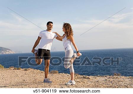 Couple stretching by the sea in a cliff in Ibiza View Large Photo Image Stock Photo - Couple stretching by the sea in a cliff in Ibiza. Fotosearch