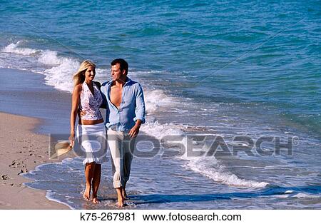 Stock Image - couple strolling along the beach. Fotosearch