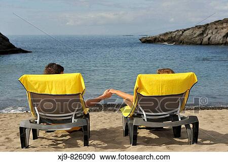 Stock Image - Couple sunbathing on the beach, Canary Islands, Spain. Fotosearch