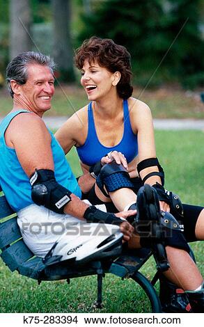 Picture - couple taking a break from rollerblading. Fotosearch