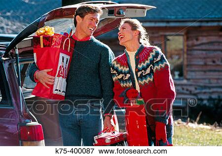 Couple taking Christmas presents out of car View Large Photo Image Stock Photo - Couple taking Christmas presents out of car. Fotosearch