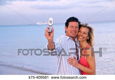 Couple taking photos of themselves with a camera phone View Large Photo Image Stock Image - Couple taking photos of themselves with a camera phone. Fotosearch