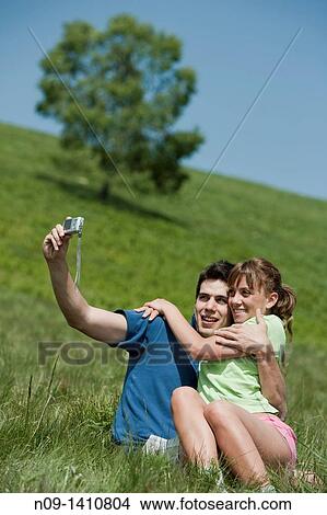 Picture - Couple taking their picture in the field. Fotosearch