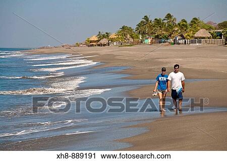 Stock Image - Couple walking along Las Peitas beach, Leon, Nicaragua. Fotosearch