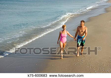 Stock Image - Couple walking along the shore. Fotosearch