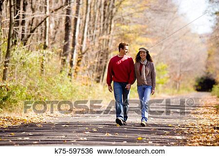 Stock Photograph - Couple walking down country road in autumn. Fotosearch