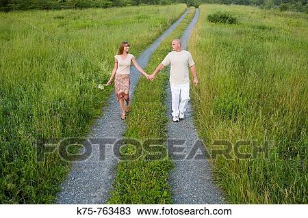 couple walking down country road holding hands View Large Photo Image Stock Image - couple walking down country road holding hands. Fotosearch