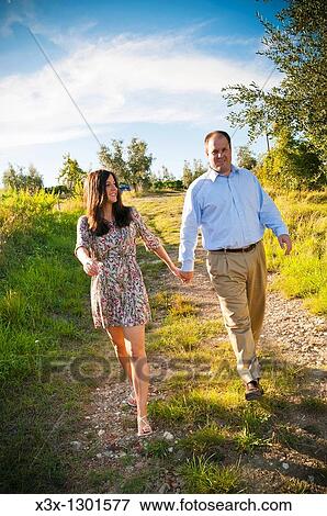 Couple walking hand in hand in a field Tuscany Italy View Large Photo Image Stock Photo - Couple walking hand in hand in a field Tuscany Italy. Fotosearch