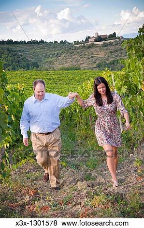 Couple walking hand in hand in a vineyard Tuscany Italy View Large Photo Image Stock Photo - Couple walking hand in hand in a vineyard Tuscany Italy. Fotosearch