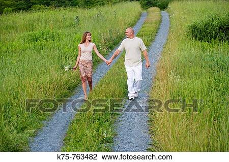 Couple walking hand in hand on country road View Large Photo Image Stock Image - Couple walking hand in hand on country road. Fotosearch