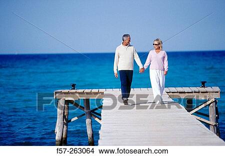 Couple walking in a wooden footbridge over the sea View Large Photo Image Picture - Couple walking in a wooden footbridge over the sea. Fotosearch