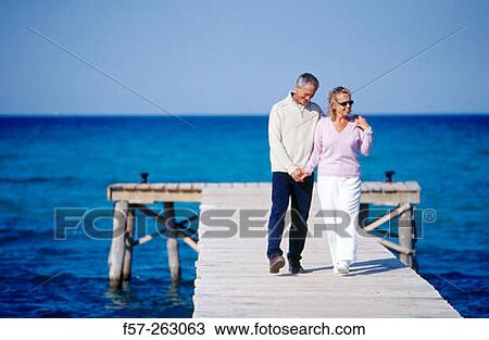 Couple walking in a wooden footbridge over the sea View Large Photo Image Stock Image - Couple walking in a wooden footbridge over the sea. Fotosearch