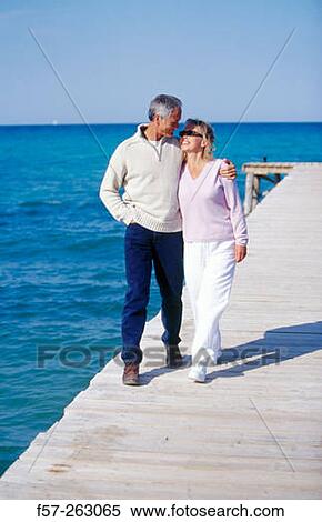 Couple walking in a wooden footbridge over the sea View Large Photo Image Stock Photography - Couple walking in a wooden footbridge over the sea. Fotosearch