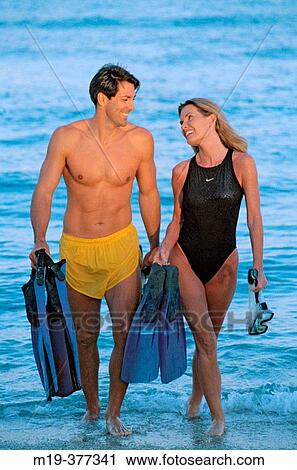 couple walking on a beach with fins and mask View Large Photo Image Stock Image - couple walking on a beach with fins and mask. Fotosearch