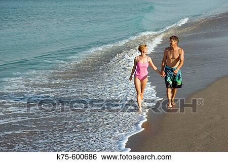Stock Photograph - Couple walking on beach. Fotosearch
