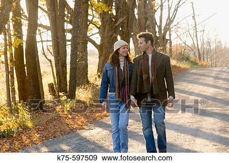 Couple walking on country road in autumn View Large Photo Image Stock Photo - Couple walking on country road in autumn. Fotosearch