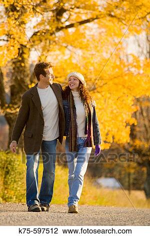 Stock Image - Couple walking on country road on a sunny day. Fotosearch