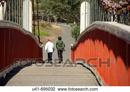 Stock Image - couple walking on red bridge. Fotosearch