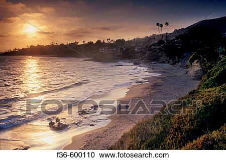 Stock Image - Couple walking on sand beach on the coast at Heisler Park, Laguna Beach, California. Fotosearch