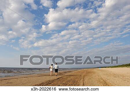 Stock Photograph - couple walking on the Lielupe beach, Jurmala, Gulf of Riga, Latvia, Baltic region, Northern Europe.. Fotosearch