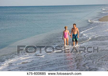 Couple walking through surf View Large Photo Image Stock Photography - Couple walking through surf. Fotosearch