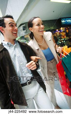 Couple walking with shopping bags in mall View Large Photo Image Stock Image - Couple walking with shopping bags in mall. Fotosearch