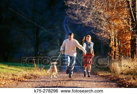 Couple walking with their dog View Large Photo Image Stock Photograph - Couple walking with their dog. Fotosearch