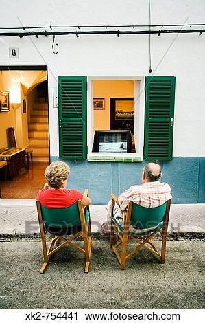 Couple watching the TV on the street, Es Migjorn Gran. Minorca, Balearic Islands, Spain View Large Photo Image Stock Image - Couple watching the TV on the street, Es Migjorn Gran. Minorca, Balearic Islands, Spain. Fotosearch