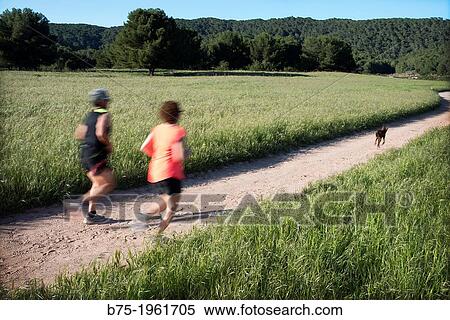couple with a dog in motion running down a country road in Menorca, Balearic Islands, Spain View Large Photo Image Stock Photography - couple with a dog in motion running down a country road in Menorca, Balearic Islands, Spain. Fotosearch