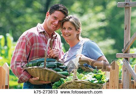 Stock Image - Couple with baskets of vegetables. Fotosearch