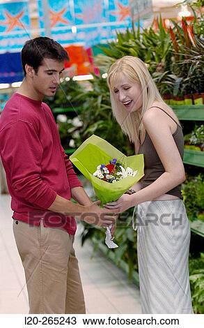 Stock Image - Couple with flower bouquet at shopping center. Fotosearch