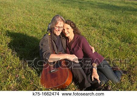Picture - Couple with guitar sitting on lawn. Fotosearch