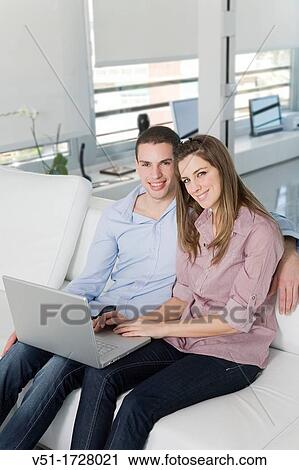 Couple with laptop at home smiling at camera View Large Photo Image Stock Image - Couple with laptop at home smiling at camera. Fotosearch