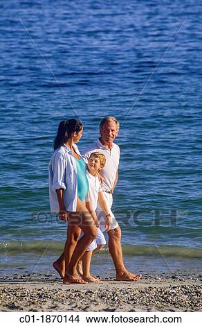 Picture - Couple with pregnant woman and boy strolling on beach. Fotosearch