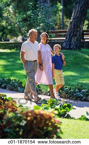Picture - Couple with pregnant woman and boy strolling in park. Fotosearch