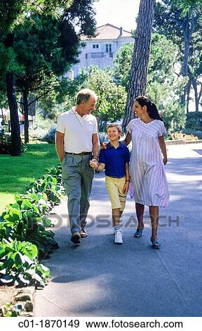 Stock Photo - Couple with pregnant woman and boy strolling in park. Fotosearch
