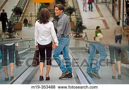 Couple with shopping bags on scalator in shopping mall View Large Photo Image Stock Photo - Couple with shopping bags on scalator in shopping mall. Fotosearch